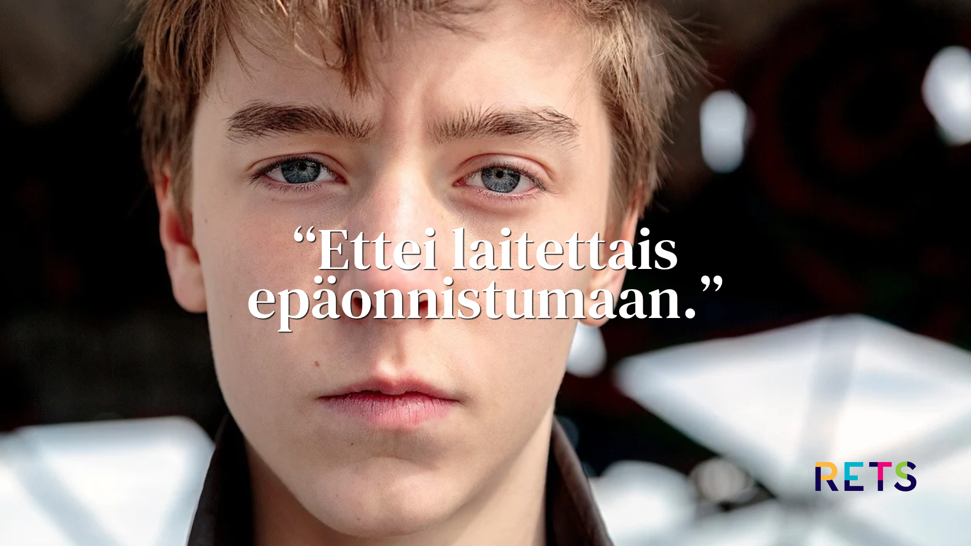 Lähikuva nuoresta pojasta, joka katsoo vakavana suoraan kameraan.